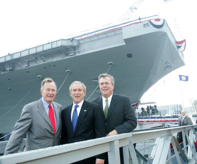 Former President George W. Bush, center, with his father, former President George H.W. Bush, and brother, former Florida Gov. Jeb Bush, right, pose in front of the aircraft carrier in October 2006. (AP/Lawrence Jackson)