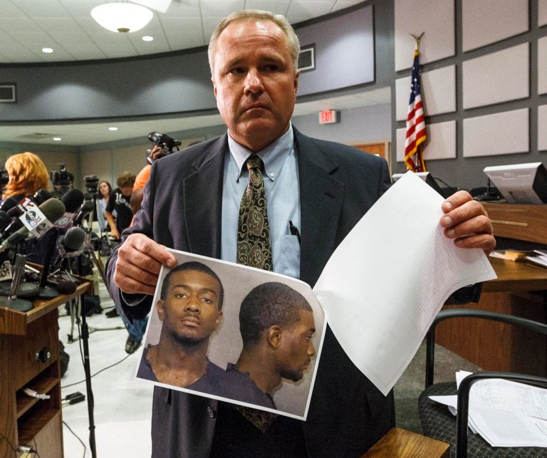   Auburn Police Chief Tommy Dawson shows headshots of suspect Desmonte Leonard, 22, of Montgomery, during a news conference, Sunday, June 10, 2012, in Auburn, Ala. Police say Leonard has been charged with capital murder and has not yet been captured, in connection with a shooting at an apartment complex near Auburn University. Dawson urged Leonard to turn himself in and also said authorities were searching for two other persons of interest. (AP Photo/Opelika-Auburn News, Vasha Hunt)  
