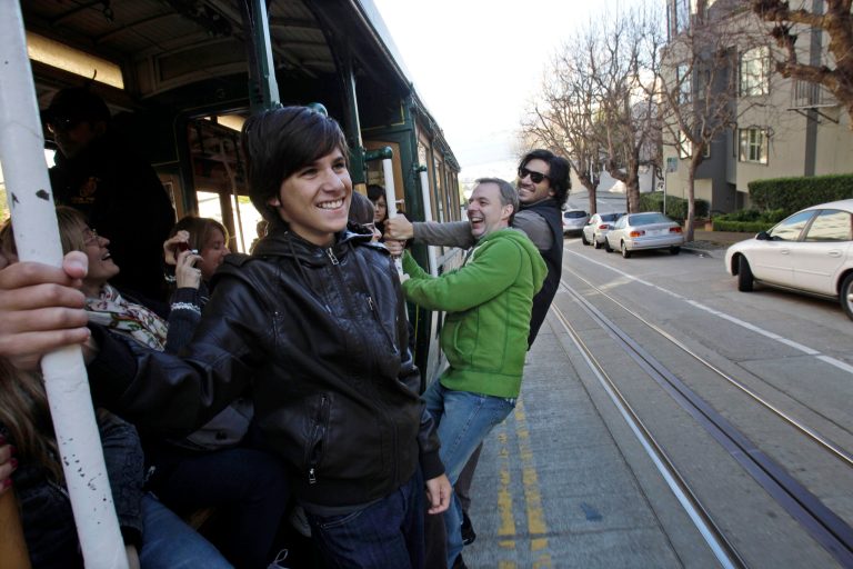 FILE - In this file photo from Jan. 21, 2011, from left, Franco Garavanno, Gustavo Ferrari and German Garavanno, who are visiting from Buenos Aires, ride a cable car up Hyde Street in San Francisco. In this city of innumerable tourist attractions, the clanging cable cars stand out as a top draw. They also stand out for the inordinate number of accidents and the millions of dollars annually the city pays out to settle lawsuits for broken bones, severed feet and bad bruises caused when 19th Century technology runs headlong into 21st Century city traffic and congestion. Recently, five passengers and two workers were injured after an inch-long bolt in the track caused their cable car to slam to a sudden stop. (AP Photo/Marcio Jose Sanchez)