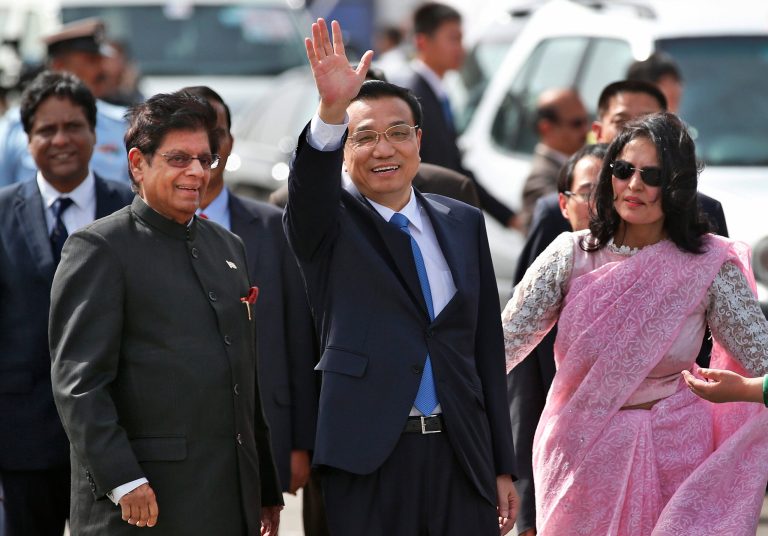 Chinese Premiere Li Keqiang waves as he is received by Indian Junior Minister for External Affairs, E. Ahamed, left, after he arrives in New Delhi, India, Sunday, May 19, 2013. Just weeks after a tense border standoff, China's new premier arrived in India on Sunday for his first foreign trip as the neighboring giants look to speed up efforts to settle a decades-old boundary dispute and boost economic ties. A woman at right is a protocol officer. (AP Photo/ Saurabh Das)