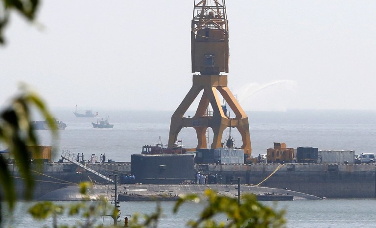 Indian navy sailors look into a submarine, believed to be the Russian-built INS Sindhuratna, on its arrival at the naval dockyard in Mumbai, India, Thursday, Feb. 27, 2014. Rescuers found the bodies of two Indian navy officers inside the naval submarine on Thursday, one day after the men went missing following an accident aboard the vessel, an official said. (AP Photo/Rajanish Kakade)