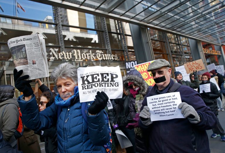 People with taped mouths hold signs and a copy of the New York Times as they show solidarity with the press during a rally in front of The New York Times building, Sunday, Feb. 26, 2017, in New York. On Friday, the White House banned several major news outlets, including The New York Times and CNN, from an off-camera briefing, known as a 