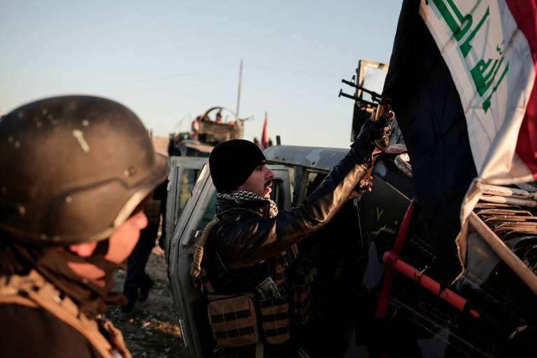 Iraqi federal police forces attach an Iraqi flag to a Humvee before going to battle against the Islamic State. (AP Photo/Bram Janssen)