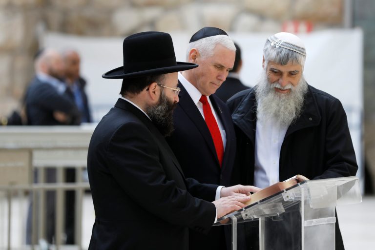 U.S. Vice President Mike Pence (C) looks at a book together with Western Wall Heritage Foundation Director General Mordechai Elias (R) and Rabbi of the Western Wall Shmuel Rabinovitch (L) during a visit to the Western Wall, Judaism's holiest prayer site, in Jerusalem's Old City, Tuesday, Jan. 23, 2018. (Ronen Zvulun/Pool photo via AP)
