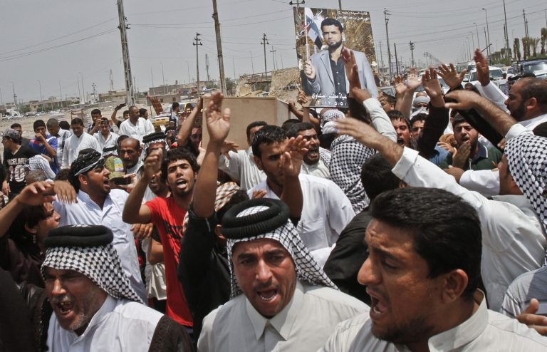 Family members of Diaa Mutashar al-Issawi, seen in the poster, chant anti-Jabhat al-Nusra and Free Syrian Army slogans during his funeral in Basra, Iraq's second-largest city, 340 miles (550 kilometers) southeast of Baghdad, Iraq, Monday, May 6, 2013. The Iraqi Shiite fighter's body was collected Monday morning at a border crossing with Iran, then carried through the streets of this southern Iraqi city as mourners vowed a similar sacrifice to protect a revered shrine in Syria. (AP Photo/ Nabil Al-Jurani)