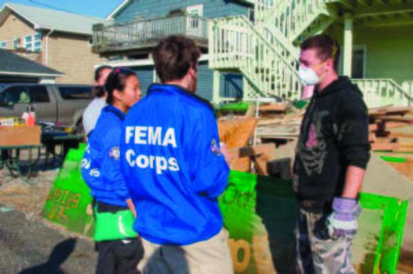 FEMA Corps team members Amy Butterfield and Sergio Tundo talk with volunteer Jason Young to ensure the owner of this residence in Sea Bright, N.J., was getting needed assistance after Hurricane Sandy destroyed much of the island. (FEMA.gov photo)