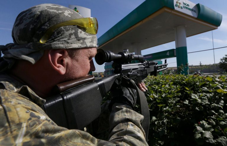 A pro-Russian rebel aims his rifle as he observes the territory in the rebel-held town of Starobesheve, eastern Ukraine, Saturday, Aug. 30, 2014. (AP Photo/Sergei Grits)