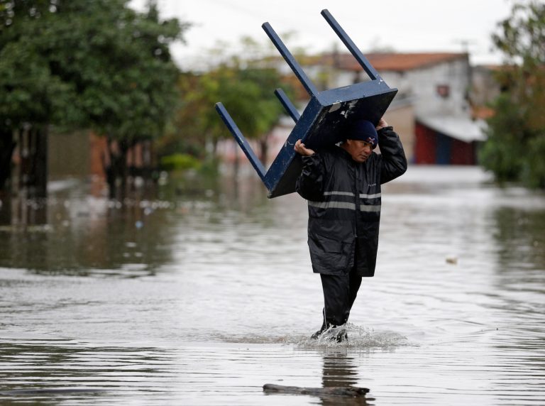 A man carries a table through a flooded street in the Tacumbu neighborhood of Asuncion, Paraguay Friday, June 27, 2014. Floods caused by torrential rains have forced the evacuation of 200,000 people living near the Paraguay and Parana rivers. (AP Photo/Jorge Saenz)