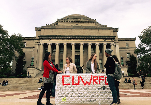 Students stand in front of the Library of the Columbia University with a mattress in support of Emma Sulkowicz's project against sexual assault, 'Carry That Weight' in which she carries her mattress around campus until her alleged rapist is expelled from the university in New York, United States on October 29, 2014. (Photo by Selcuk Acar/Anadolu Agency/Getty images)