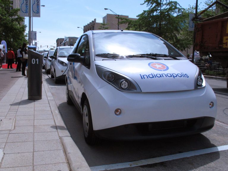Electric cars known as Bluecars are lined up in downtown Indianapolis at a car-charging station that debuted on Monday, May 19, 2014, and is part of an electric car-sharing service coming to Indiana's capital. French company Bollore Group is investing $35 million in the project that won't be up and running until year's end, when 125 cars will be available at 25 charging sites around the city. (AP Photo/Rick Callahan.)