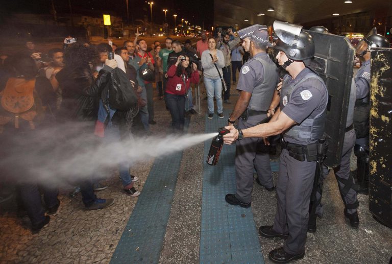 A police officer pepper sprays strikers and protesters during a clash with riot police in front of the Ana Rosa metro station, in an ongoing subway strike by operators, in Sao Paulo, Brazil, Monday, June 9, 2014. Authorities are deeply worried about the strike because the subway is the main means of transportation for World Cup fans scheduled to attend Thursday's opening match when Brazil takes on Croatia. The stadium is about 20 kilometers (12 miles) east of central Sao Paulo, where most tourists stay. (AP Photo/Mario Angelo)