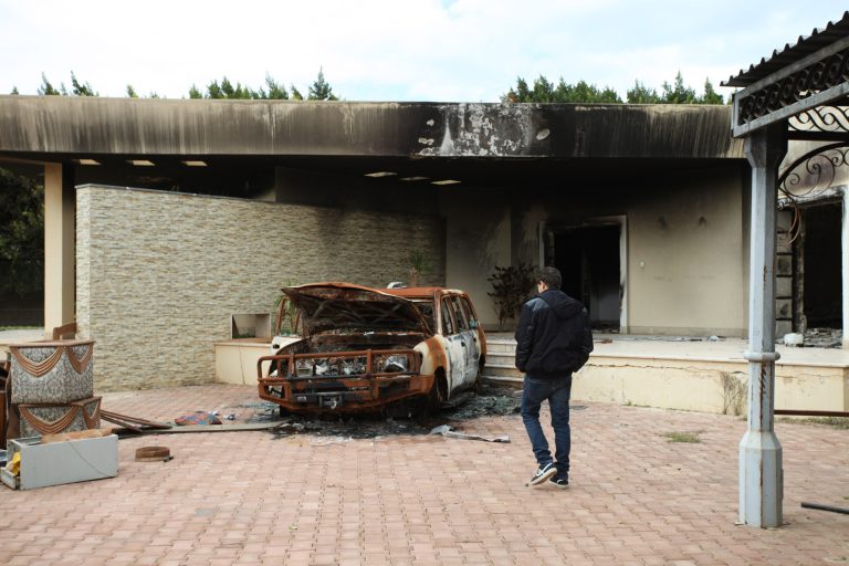 A man walks near a charred vehicle at the entrance of the damaged American consulate building in Benghazi, Libya, on Feb. 16, 2013. (AP Photo/Mohammad Hannon)
