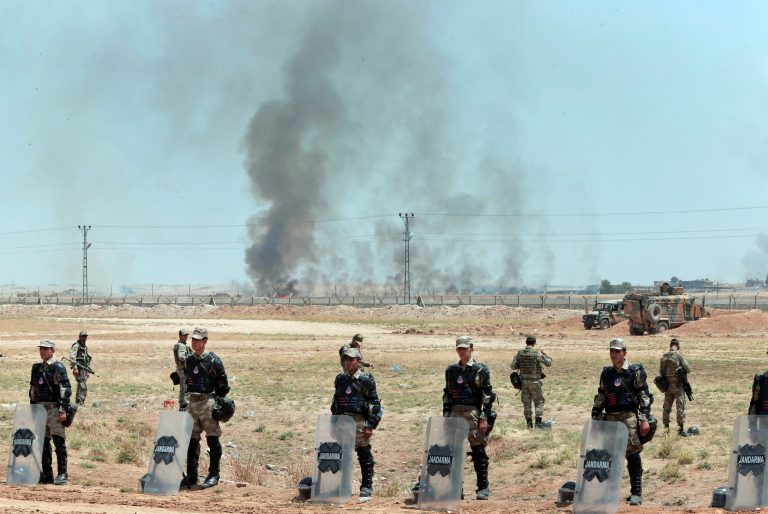 Turkish soldiers guard the border area with Syria in Akcakale, southeastern Turkey, as smoke from a fire caused by a US-led airstrike rises over the outskirts of Tal Abyad, Syria, Monday, June 15, 2015. (AP Photo/Lefteris Pitarakis)