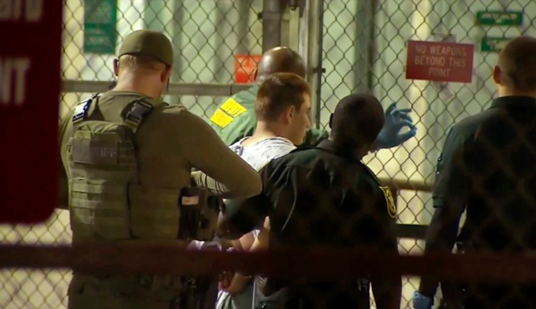 Police take 19-year-old Nikolas Cruz into Broward County jail on Thursday. Cruz was charged with 17 counts of premeditated murder Thursday morning after being questioned for hours by state and federal authorities. (WPLG-TV via AP)