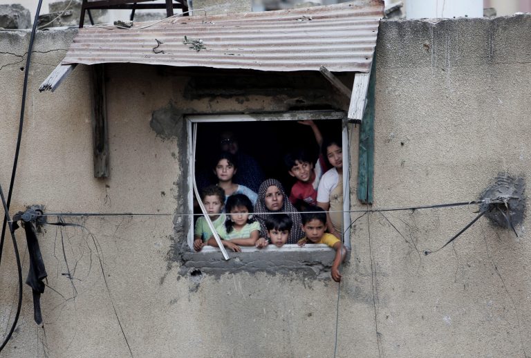 FILE - In this Monday, July 21, 2014, file photo, a Palestinian family watches rescuers searching for bodies and survivors under the rubble of homes which were destroyed by an Israeli missile strike, in Gaza City. Disagreement over whether to lift the Gaza blockade is a key stumbling block to ending more than two weeks of fighting between the Islamic militant Hamas and Israel. Some in Gaza say they would rather endure more fighting than return to life under blockade. (AP Photo/Khalil Hamra, File)