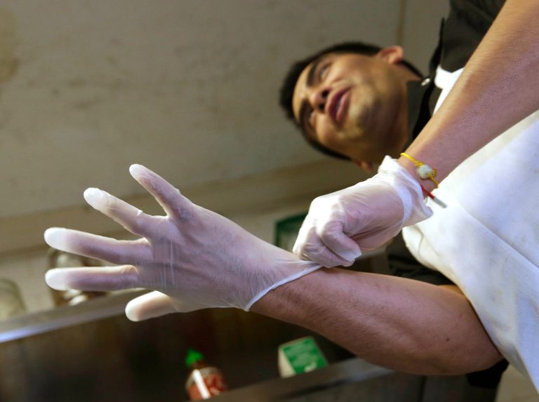 FILE - In this March 12, 2014 file photo, Luis Escamilla puts on gloves before cutting prosciutto at the Hock Farm Restaurant in Sacramento, Calif. California's chefs and bartenders could resume legally handling food with their bare hands under a bill headed to the governor's desk that would repeal an unpopular regulation. The bill, AB2130, passed its final legislative hurdle Thursday, June 26, 2014. with a 32-0 vote in the state Senate. (AP Photo/Rich Pedroncelli,File)