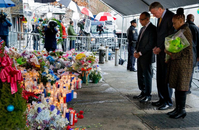 From left, Pastor Michael Durso, New York City Mayor Bill de Blasio and New York City first lady Chirlane McCray visit a makeshift memorial Tuesday near the site where New York Police Department officers Rafael Ramos and Wenjian Liu were shot and killed in the Brooklyn borough of New York. (AP Photo/Craig Ruttle)