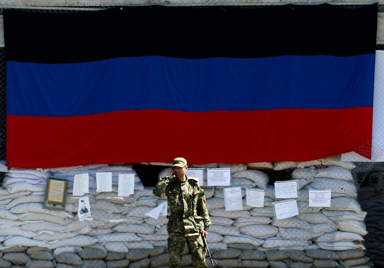 A pro-Russian gunman speaks by phone in front of the city hall decorated with the flag of self-proclaimed Donetsk People's Republic, in the center of Slovyansk, eastern Ukraine, Thursday, May 8, 2014. A strong majority of Ukrainians want their country to remain a single, unified state and this is true even in the largely Russian-speaking east where a pro-Russia insurgency has been fighting for autonomy, a poll released Thursday shows. The survey results were released as the pro-Russia forces were considering whether to go ahead with a referendum on autonomy planned for Sunday in defiance of a call from Russian President Vladimir Putin to delay the vote. A decision was expected later in the day. (AP Photo/Darko Vojinovic)
