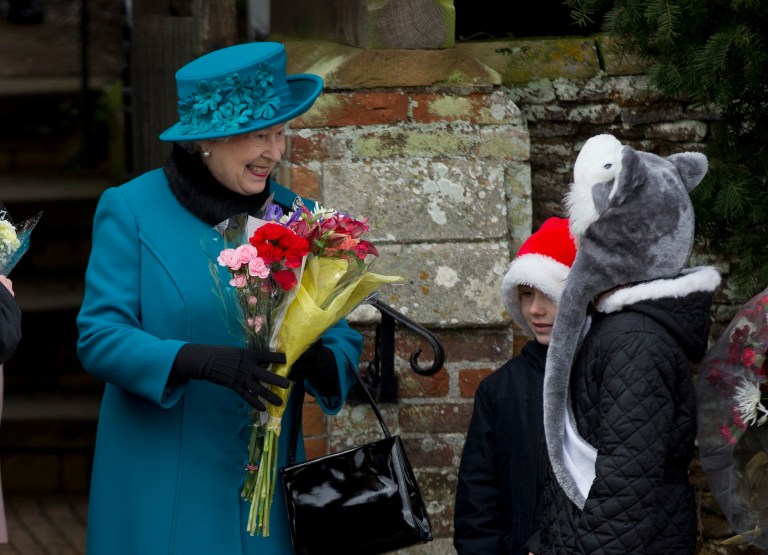   Britain's Queen Elizabeth II receives flowers from children after attending the British royal family's traditional Christmas Day church service in Sandringham, England, Tuesday, Dec. 25, 2012. (AP Photo/Matt Dunham)  