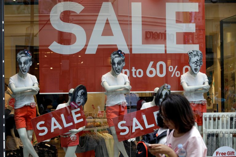 A woman walks by sale signs at Seoul shopping district, South Korea, Thursday, July 24, 2014. South Korea's government unveiled stimulus plans Thursday after the shock of a deadly ferry sinking slowed economic growth to the lowest level in three quarters. (AP Photo/Lee Jin-man)