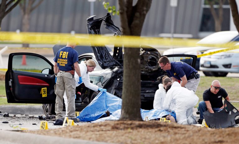 In this May 4, 2015 file photo, FBI crime scene investigators document the area around two deceased gunmen and their vehicle outside the Curtis Culwell Center in Garland, Texas. (AP Photo/Brandon Wade)