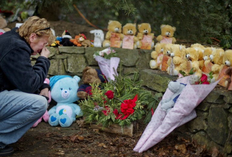 A person kneels at a memorial for the victims of the Sandy Hook Elementary massacre. 