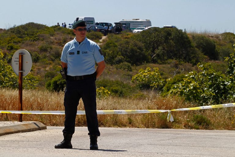 A Portuguese Republican Guard policeman stands guard by a cordoned-off area with other officers, background, in Praia da Luz, Lagos, southern Portugal, Monday, June 2, 2014. Police investigating the disappearance of Madeleine McCann cordoned off Monday an area of scrubland near where the British girl vanished seven years ago. Officers placed yellow-and-white police tape around the waste ground, which is mostly level and slightly larger than a soccer field, and were expected to conduct a forensic examination of the area in the coming days. (AP Photo/Francisco Seco)
