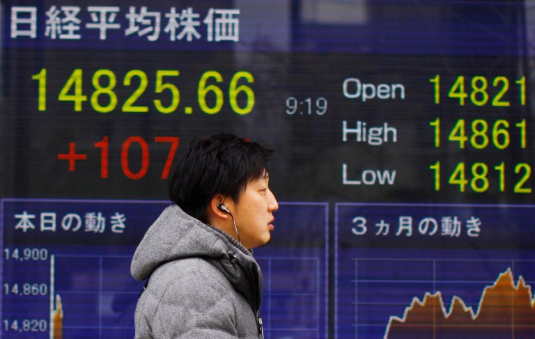 A man walks outside a securities firm in Tokyo, Wednesday, Feb. 12, 2014. Tokyo stocks jumped in early trading Wednesday, a day after a surge on Wall Street that followed reassurance from the new head of the U.S. Federal Reserve about continued low-interest rate policies. (AP Photo/Junji kurokawa)