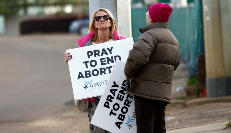 Kami Bullock, left, and Barbara Beavers, both anti-abortion supporters, stand with their signs outside the Jackson Women's Health Organization clinic in Jackson, Miss., and attempt to elicit support from passing drivers, Thursday, March 8, 2018. The facility is currently Mississippi's only abortion clinic. Abortion law experts say House Bill 1510, which passed the Mississippi House on Thursday and the Senate on Tuesday, and would ban most abortions after 15 weeks of pregnancy, could be the nation's most restrictive if signed into law.