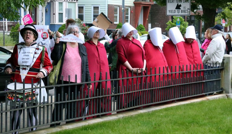 In this Thursday, May 23, 2019, photo, women dressed as characters from the "The Handmaid's Tale" protest outside a fundraiser for the Rhode Island Senate Democrats political action committee in Providence, R.I. 