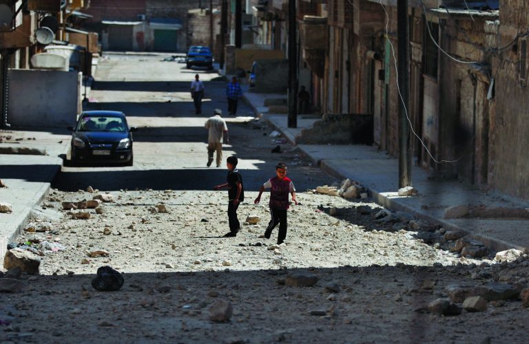 FILE - In this Sunday, Aug. 19, 2012 file photo, two Syrian boys play on a street next to a building hit by a Syrian government airstrike in Aleppo, Syria. Its forces stretched thin on multiple fronts, President Bashar Assad's regime has significantly increased its use of air power against Syrian rebels in recent weeks, causing mounting civilian casualties. The shift is providing useful clues about the capability of the air force as Western powers consider the option of enforcing a no-fly zone over the northern part of the country.(AP Photo/ Khalil Hamra, File)