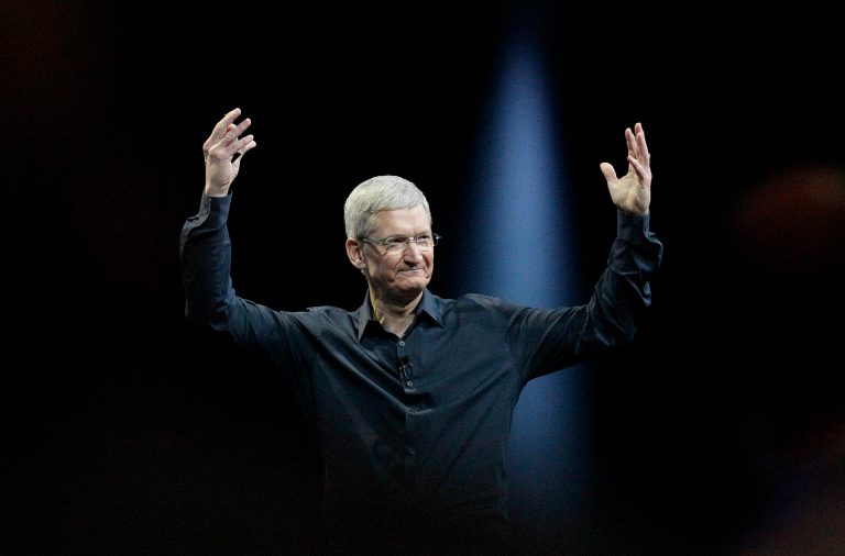 Apple CEO Tim Cook throws his hands in the air onstage.