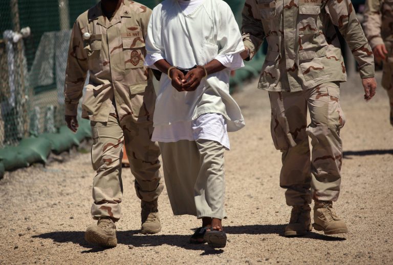 U.S. military guards move a detainee on September 16, 2010 in Guantanamo Bay, Cuba. (Photo by John Moore/Getty images)
