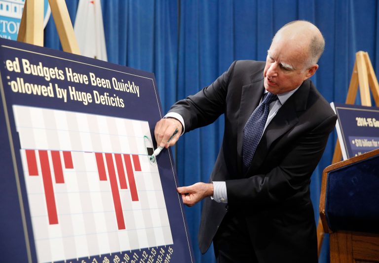 On a chart showing the states budget deficits in red the past few years, Gov. Jerry Brown circles the black line showing a surplus of funds for the upcoming year during a news conference where he unveiled his proposed 2014-15 state budget. With the an increase in tax receipts, Brown is proposing a spending plan that includes a 8.5 percent increase in general fund spending coupled with a dedication to pay down the state's debt by more than $11 billion.(AP Photo/Rich Pedroncelli)
