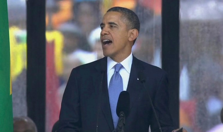 US President Barack Obama speaks to the assembled crowds at the FNB Stadium in Soweto, South Africa, in the rain for a memorial service for former South African President Nelson Mandela, Tuesday. (AP/SABC Pool)
