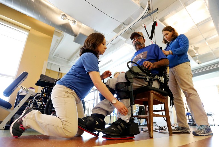 Physical therapists Julietta Douglas (left) and Chara Rodriguez (right) help Pedro Lozano, 56, into the Ekso exoskeleton, to help him walk, during therapy Thursday April 10, 2014 at the University Health System's Reeves Rehabilitation Center. Lozano is paralyzed on his left side after suffering a stroke Dec. 27, 2013. (AP Photo/San Antonio Express-News, Edward A. Ornelas) **MAGS OUT NO SALES SAN ANTONIO OUT**