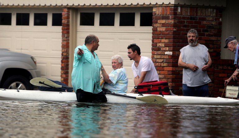 People walk out of their flooded Meyerland streets, Sunday, Aug. 27, 2017, in Houston, Texas. The remnants of Hurricane Harvey sent devastating floods pouring into Houston on Sunday as rising water chased thousands of people to rooftops or higher ground. (Mark Mulligan/Houston Chronicle via AP)