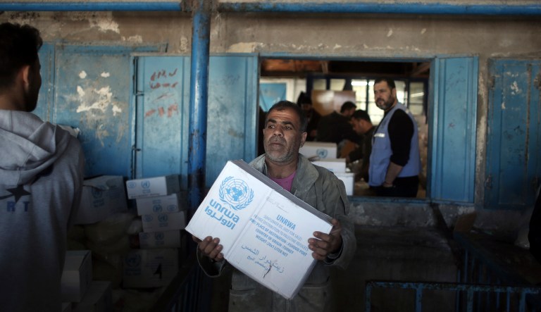Palestinians receive food aid at a U.N. Relief and Works Agency warehouse in the Shati refugee camp, Gaza City, on Jan. 14, 2018. (AP Photo/ Khalil Hamra)