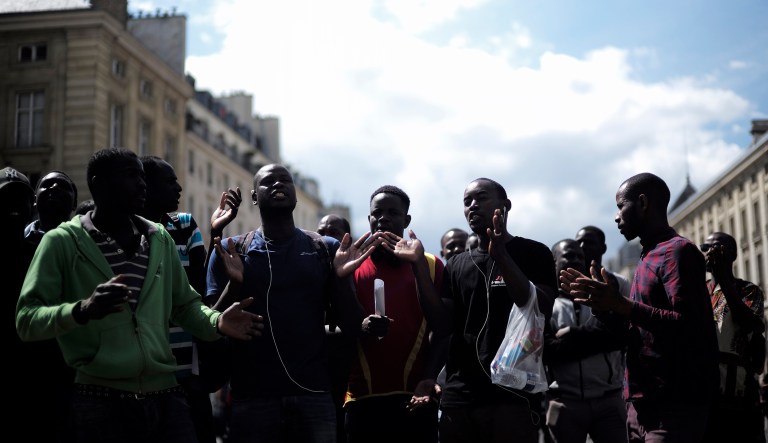 Migrants shout outside the Pantheon monument, where illustrious French figures are buried, in the Latin quarter of Paris, Friday, July 12, 2019. Dozens of migrants invaded the Pantheon.