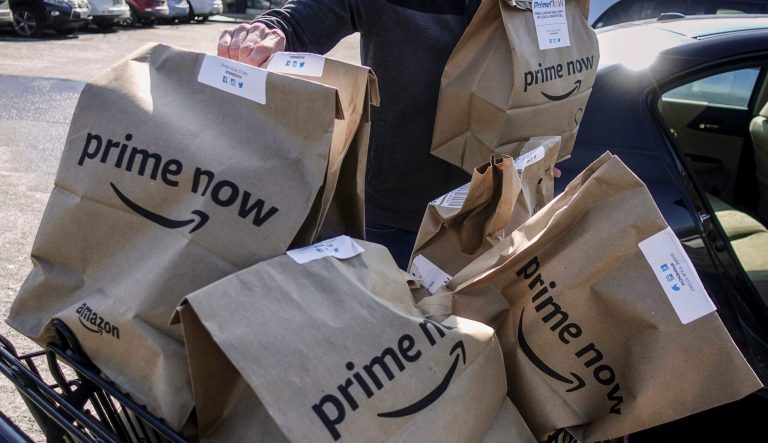 Amazon Prime Now bags full of groceries are loaded for delivery by a part-time worker outside a Whole Foods store, Thursday, Feb. 8, 2018, in Cincinnati.