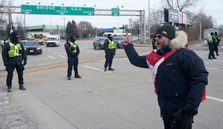 A protester yells at police officers as demonstrators prepare to leave in advance of police enforcing an injunction against their demonstration, which has blocked traffic across the Ambassador Bridge by protesters against COVID-19 restrictions, in Windsor, Ontario, on Saturday.