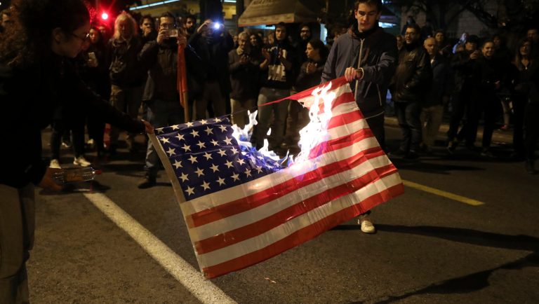 Protesters burn an American flag outside the US Embassy during a rally in Athens, Saturday, Nov. 17, 2018. Several thousands people march to the U.S. Embassy in Athens under tight police security to commemorate a 1973 student uprising that was crushed by Greece's military junta, that ruled the country from 1967-74.