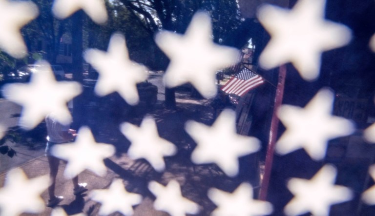 An American flag is displayed outside a store while seen through another flag along the main business street in Newtown, Penn. Tuesday, June 16, 2020.                                                                                      