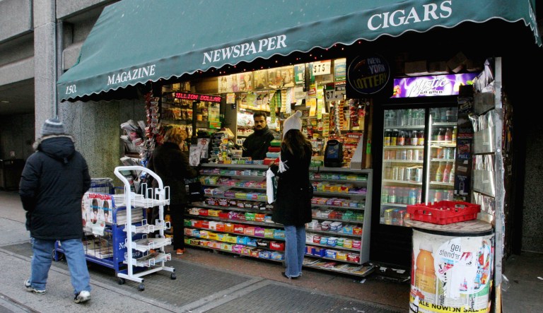Faisal Jamil, second from right, sits inside an outdoor newsstand where he works on New York's upper east side.