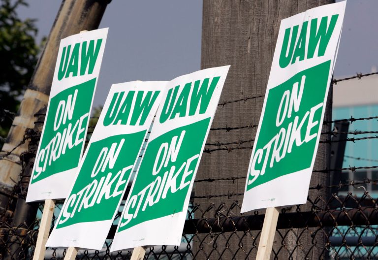 United Auto Workers strike signs are displayed on a fence at the General Motors service parts operation in Ypsilanti, Mich.