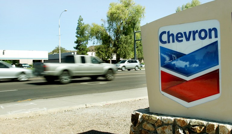 Cars drive past a fuel price sign at a local Chevron station.