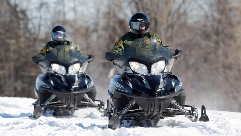 In this Feb. 10, 2011 photo, U.S. Border Patrol agents Janice Jones, left, and Glenn Pickering ride snowmobiles along the St. Lawrence River in Massena, N.Y.