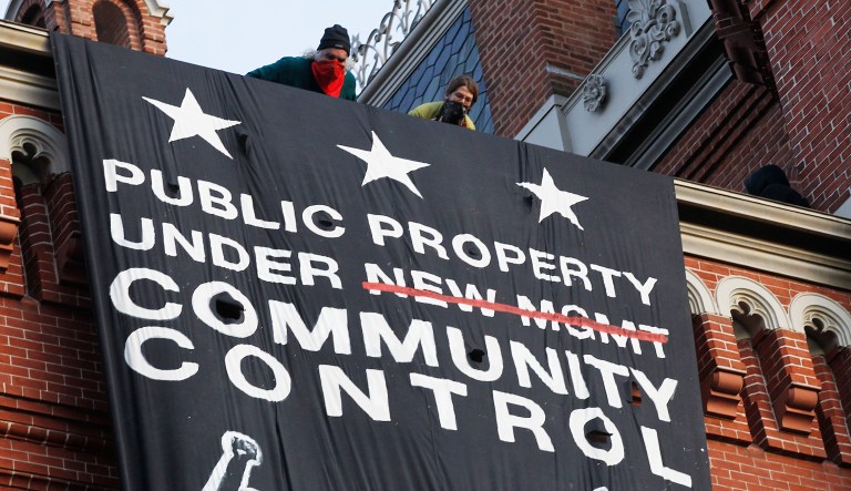 A group of protesters look out from the roof after hanging a banner on the Franklin School building, at one time a homeless shelter, in Washington, Saturday, Nov., 19, 2011.