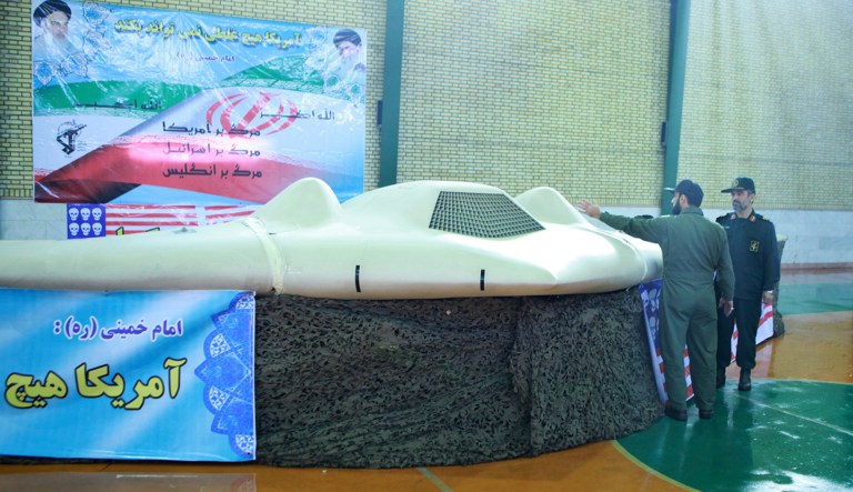 This photo released on Thursday, Dec. 8, 2011, by the Iranian Revolutionary Guards, claims to show US RQ-170 Sentinel drone which Tehran says its forces downed earlier this week, as the chief of the aerospace division of Iran's Revolutionary Guards, Gen. Amir Ali Hajizadeh, right, listens to an unidentified colonel, in an undisclosed location, Iran.