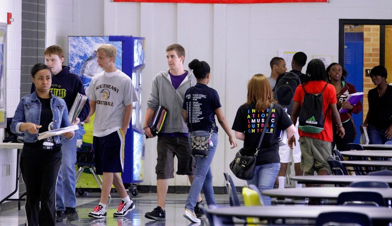 High school students are seen walking through the hallway. 
